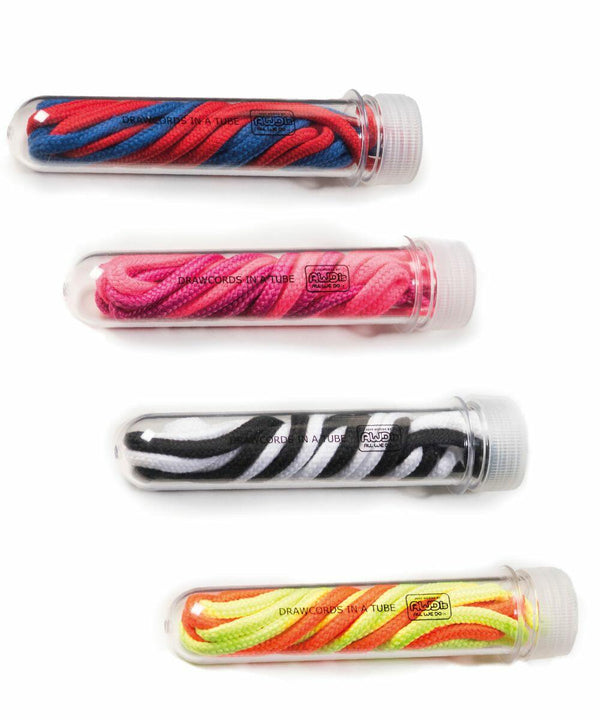 Four transparent tubes each contain different pairs of AWDis Just Hoods JH200 shoe drawcords: blue and red, pink, black and white, and neon green and orange.