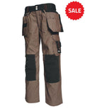 A pair of brown Tranemo TR7160_27 work pants with multiple pockets, black knee reinforcements, and tool loops. The pants have a relaxed fit and are designed for durability and functionality during tough labor activities.