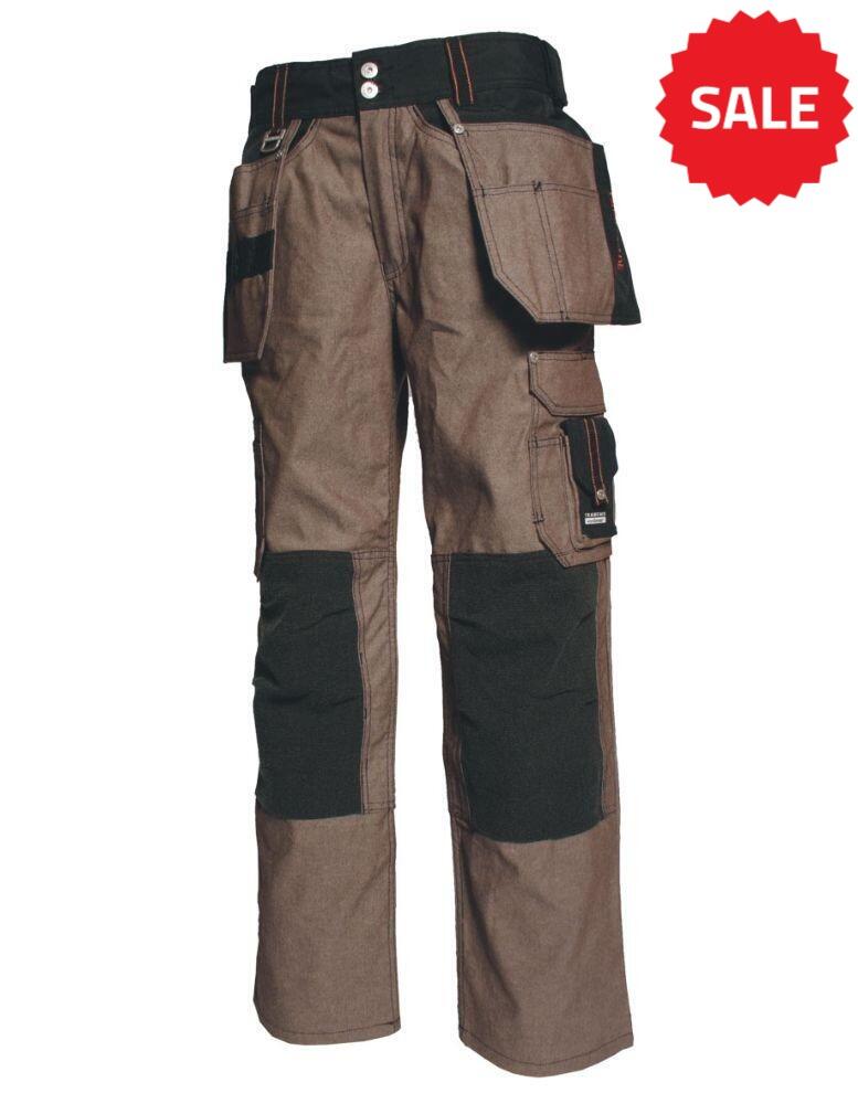 A pair of brown Tranemo TR7160_27 work pants with multiple pockets, black knee reinforcements, and tool loops. The pants have a relaxed fit and are designed for durability and functionality during tough labor activities.