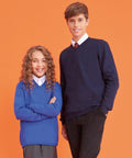 Two children, a girl and a boy, stand against an orange background. Both are wearing AC003 by AWDis Academy, with white shirts underneath. The girl has curly hair and the boy has short hair; both are smiling.