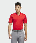 A person wearing a red AD002 by adidas and gray pants, with a gray belt, stands against a plain white background.