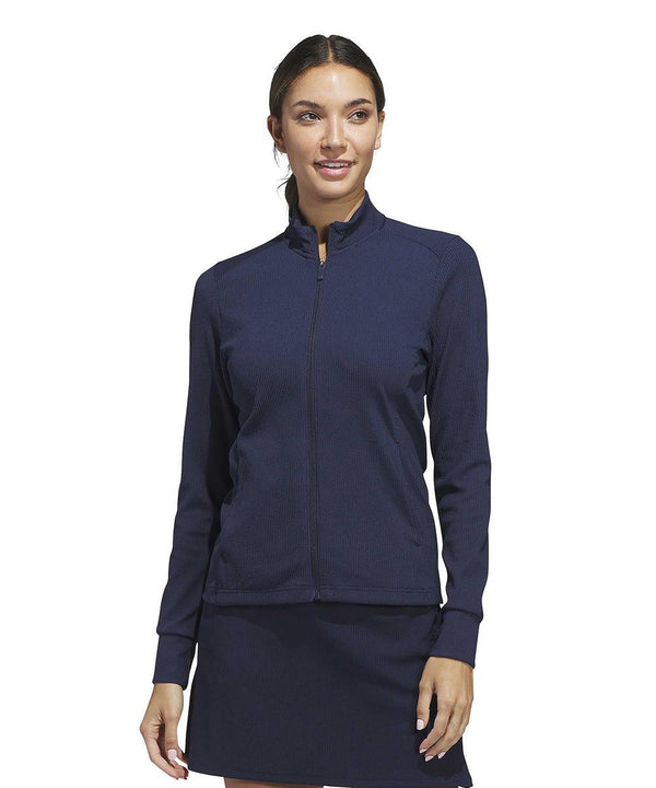 A woman faces forwards against a plain white background, wearing the adidas Women’s Performance Texture Full-Zip Jacket in navy blue.