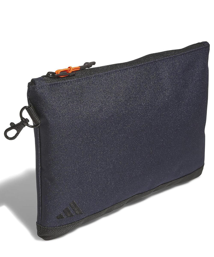 The adidas Valuables pouch is a rectangular, dark blue zippered pouch with a black bottom and an orange zip pull, shown standing upright against a white background.