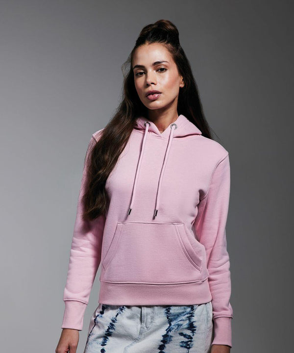 A person wearing an Anthem AM003 light pink hoodie with drawstrings and a front pocket stands against a plain gray background. Their long hair is styled with a top bun. They are also wearing white pants with blue tie-dye patterns.