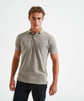 A man with curly hair stands against a plain white background, wearing an Asquith & Fox AQ015 grey short-sleeve polo shirt and black pants.