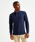 A person is wearing a navy blue long-sleeve Asquith & Fox AQ030 polo shirt and beige pants, standing against a plain white background.