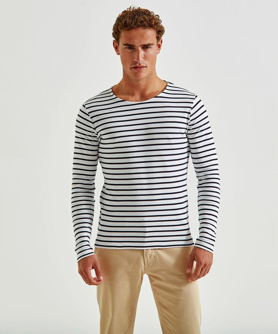 A person with curly hair is standing against a plain white background. They are wearing an AQ070, a long-sleeved, white and navy blue striped shirt by Asquith & Fox, and beige pants. Their arms are relaxed by their sides and they are looking straight ahead.
