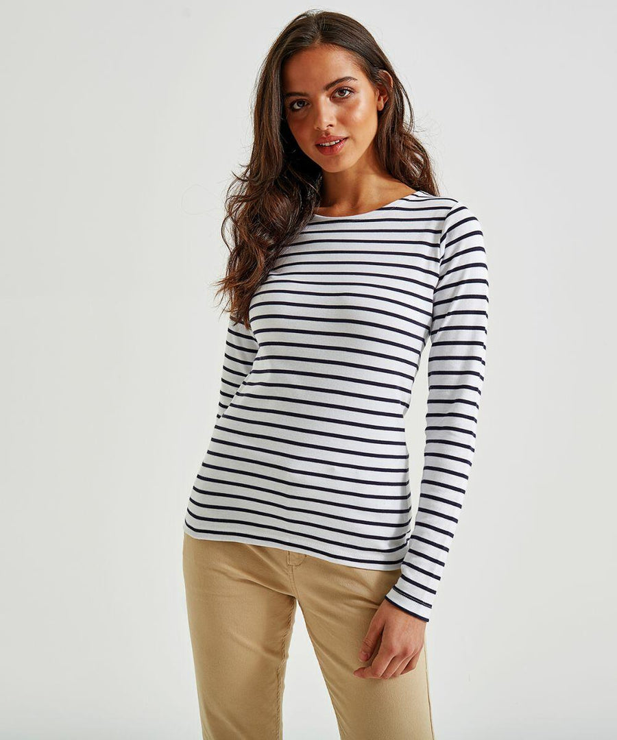 A woman with long brown hair wearing an Asquith & Fox AQ071 and beige pants poses against a plain white background. She stands with one hand relaxed at her side and a gentle smile on her face.