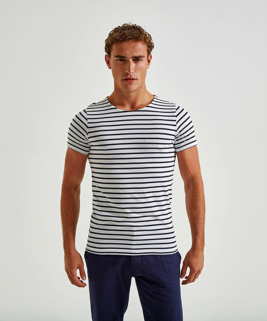 A man standing against a plain background, wearing an Asquith & Fox AQ072 fitted, short-sleeved, white t-shirt with black horizontal stripes, and dark blue pants. He has short, curly hair and is facing the camera with a neutral expression.