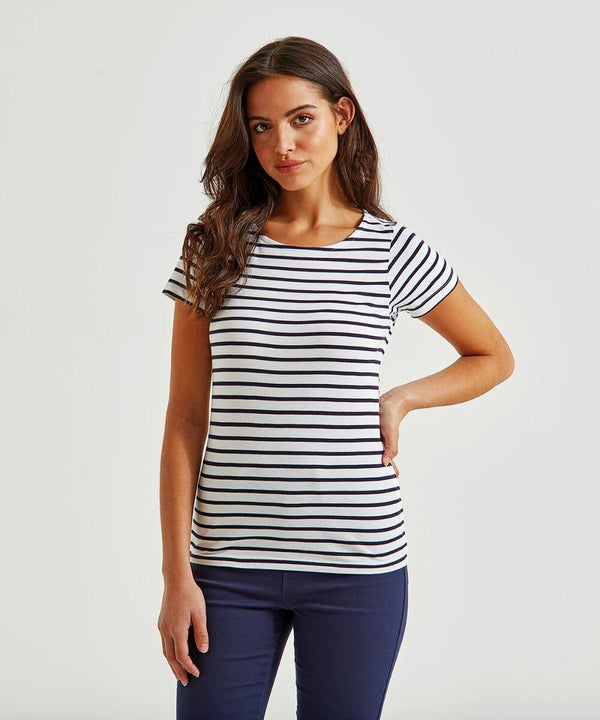 A woman with long, brown hair stands against a plain white background. She is wearing an Asquith & Fox AQ073 short-sleeve shirt in white and black stripes and dark blue pants. She has one hand on her hip and appears confident, looking directly at the camera.