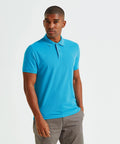 A man wearing an Asquith & Fox AQ082 blue polo shirt and gray pants stands against a white background.