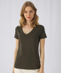 A woman with shoulder-length blonde hair is wearing a dark green B&C Collection B119F and off-white pants. She stands in front of a plain white background, looking directly at the camera with a neutral expression.