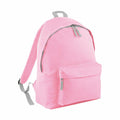 The Bagbase B125J backpack comes in pink and includes two adjustable gray straps. It features a spacious main compartment with a zipper and an additional smaller front pocket, also secured with a zipper.