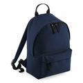 The Bagbase B125S is a navy blue backpack featuring a zippered front pocket and two main zippers. It includes adjustable shoulder straps and a top handle, and is displayed upright against a white background.