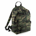 A Bagbase B125S backpack featuring a green and brown camouflage design comes with a front pocket and black zippers. It includes adjustable shoulder straps and a black carrying handle on top, displayed against a white background.