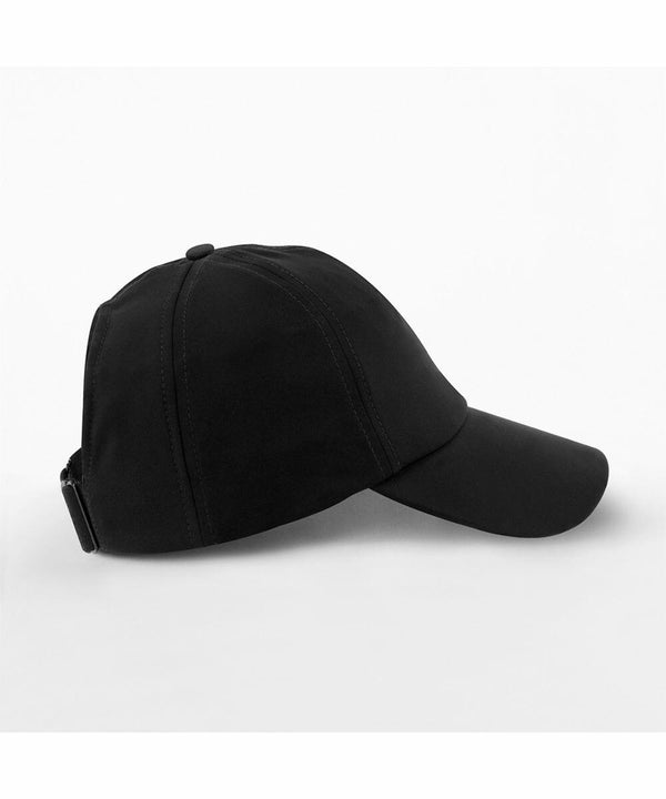 A side view of a plain black Beechfield B173R baseball cap against a white background. The cap features a curved bill and an adjustable strap at the back. The design is simple and unadorned, highlighting the sleek and minimalist style of the cap.
