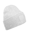 A plain white beanie knitted hat with a wide ribbed folded brim and a blank rectangular patch on the front, shown against a white background.
