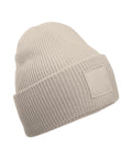 Beanies: Light beige knitted beanie with a folded brim and a blank rectangular patch on the front, shown against a white background.