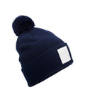 A navy blue Beanies knitted beanie with a bobble and a blank white rectangular patch on the front, shown on a plain white background.