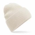 The Beechfield B384R beanie is displayed against a white background, showcasing its cream-colored ribbed knit texture. It features a folded cuff, emphasizing the thick and warm material.