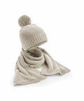 A Beechfield B401R beige knitted beanie with a pom-pom and an accompanying matching scarf are showcased.