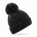 The Beechfield B406B, a black knit beanie featuring a pom-pom on top, is displayed against a plain white background.