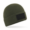 Beechfield's B442R is a ribbed olive green knit beanie featuring a black rectangular patch on the front, shown against a white background.