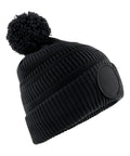 Beanies: Black knitted hat with ribbed texture, folded brim, large pom-pom top, and round front patch.