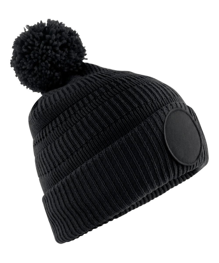 Beanies: Black knitted hat with ribbed texture, folded brim, large pom-pom top, and round front patch.