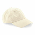 The Beechfield B652N is a plain beige baseball cap with a curved brim, showcasing stitching details on the seams and the brim. The cap is positioned at an angle, emphasizing its simple design and neutral color.