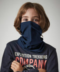 A young person with medium-length brown hair stands wearing a blue Beechfield B900B pulled up over their nose and mouth. They are dressed in a dark shirt with "Expedition Trekking Company" written on the front. The background is plain gray.