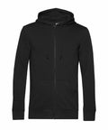 The BA002 black zip-up hoodie by B&C Collection, featuring drawstrings and front pockets, is displayed against a plain white background.