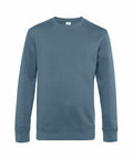 The BA010 by B&C Collection is a muted blue plain, long-sleeved sweatshirt with a crew neck. It features ribbed cuffs and a ribbed hem and is displayed on a simple white background.