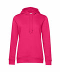 The B&C Collection BA01F is a bright pink hoodie featuring a front pocket and drawstring hood, showcased against a white background. It includes ribbed cuffs and hem, providing a casual and comfortable appearance.