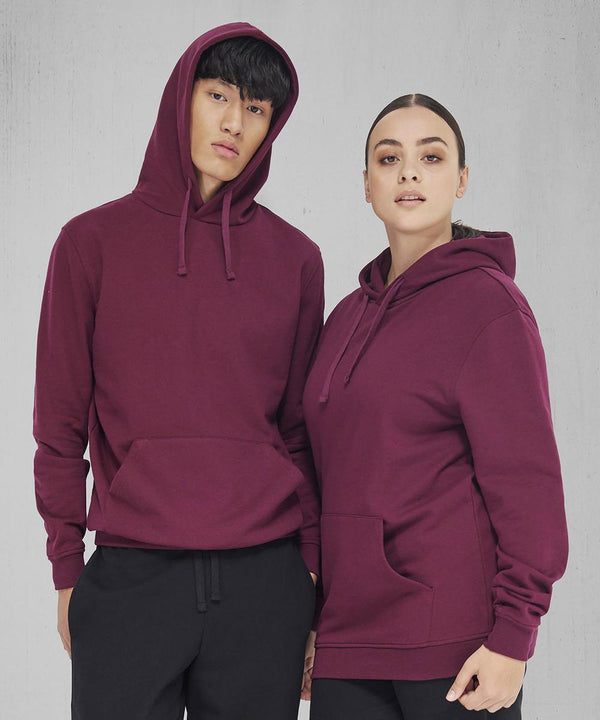 Two people stand side by side against a plain grey background, both wearing matching B&C Collection B&C ID.223 maroon hoodies with front pockets and black trousers—one with the hood up, the other with it down.