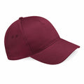 The BC015 by Beechfield is a maroon baseball cap featuring a curved brim and two ventilation holes on each side.