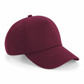 A Beechfield BC025 baseball cap in burgundy, featuring a curved brim and ventilation holes on the top panels. The cap is angled to highlight its simple and classic design.