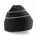 A Beechfield BC042 black knit beanie with two white horizontal stripes near the top, resting on a flat surface.