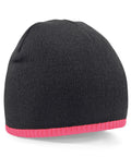 The Beechfield BC044 is a black knit beanie featuring a pink trim at the bottom.