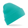 The Beechfield BC045, a vibrant teal knit beanie featuring a folded brim, is showcased against a plain white background, seemingly suspended in mid-air with a faint shadow cast below it.