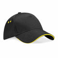 The Beechfield BC15C is a black baseball cap featuring yellow accents along the edge of the brim and two small yellow ventilation holes on the side, showcased against a white background.