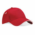 A Beechfield BC15C red baseball cap featuring a curved brim adorned with a thin white trim and two small white ventilation holes on each side. The cap is set against a plain white background.