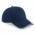 The BC25C by Beechfield is a blue baseball cap with a curved visor and white trim on the brim, displayed against a white background. This cap also features ventilation holes on the top.