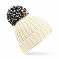 The BC390 by Beechfield is a cream-colored knit beanie, featuring a large multicolored pom-pom on top, ribbed texture, and a folded brim.