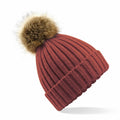 The BC412 from Beechfield is a rust-colored knitted beanie featuring a large, fluffy faux fur pom-pom on top, complete with a ribbed texture and a folded cuff.