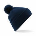 The Beechfield BC426 is a navy blue knit beanie featuring a rolled brim and a pom-pom on top, photographed against a white background.