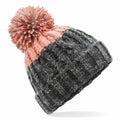 The BC437 beanie by Beechfield features a pink top with a pom-pom, transitioning to a gray lower half, and showcases a cable pattern.
