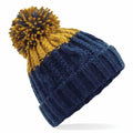 The BC437 beanie by Beechfield showcases a ribbed texture and cable-knit patterns, featuring a vibrant blue lower half transitioning to a yellow upper half, all topped with an eye-catching yellow and blue pom-pom.