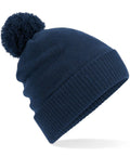 A Beechfield BC439 navy blue knitted beanie featuring a pom-pom on top.