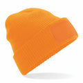 A Beechfield BC440 knit beanie in orange, featuring a wide rim and a rectangular patch on the front.